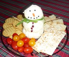 a glass plate with crackers, tomatoes and cheese on it next to a snowman