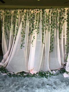 the curtain is covered with ivy and flowers on it's side, along with other greenery