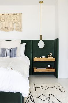 a bedroom with green headboard, white bedding and rugs on the floor