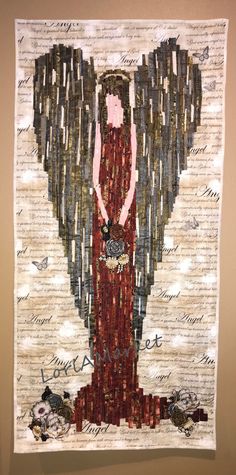 an angel made out of words and paper on a white wall with a red dress