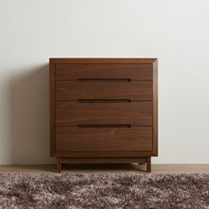 a wooden dresser sitting on top of a carpeted floor next to a white wall