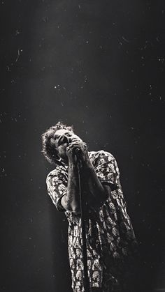 a man standing on top of a stage holding his head to his face while holding a microphone