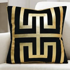 a black and gold pillow sitting on top of a white couch