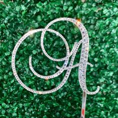 a cake topper with the letter g on it in front of some green grass