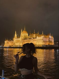 a woman standing in front of a large building with lights on it's sides