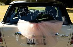 a car with a pink tulle tied to it's rear window that says just married