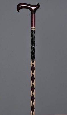 an old wooden walking stick with black and white designs on it's handle, in front of a gray background