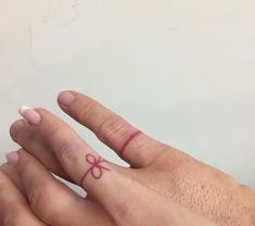 a person with a small bow tattoo on their left hand, holding onto another persons finger