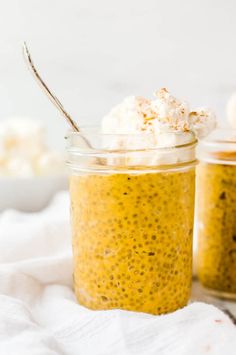 two jars filled with food sitting on top of a white cloth next to a spoon