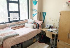 a dorm room with a bed, desk and window