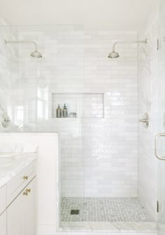 a white bathroom with marble counter tops and tile flooring, along with a walk in shower