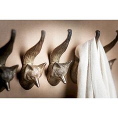 three metal animal heads mounted to the side of a wall next to a white towel