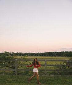 a woman is running in the grass with a frisbee