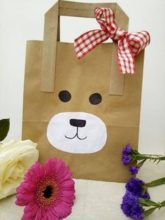 a brown paper bag with a bear face on it and flowers in the foreground