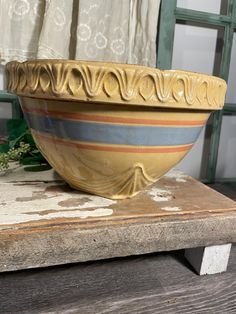 a yellow bowl sitting on top of a wooden table next to a green planter