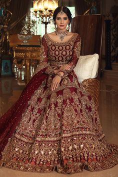 a woman sitting in a chair wearing a red and gold wedding dress