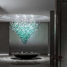 a large glass chandelier hanging from the ceiling in a room with grey walls