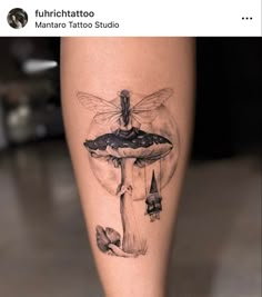 a tattoo on the leg of a woman with a dragon flying over it and mushrooms