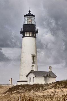 a lighthouse on top of a hill under a cloudy sky