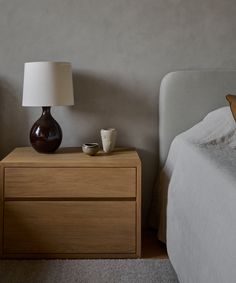 a bedroom with a bed, night stand and lamp on the nightstand next to it