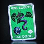 a green and white patch with a purple dragon on it's side, in the dark