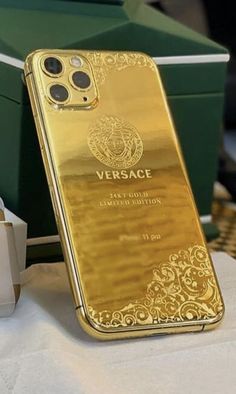 a gold iphone case sitting on top of a white table next to a green box