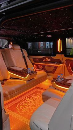 the interior of a luxury car with its lights on and leather seats in front of it