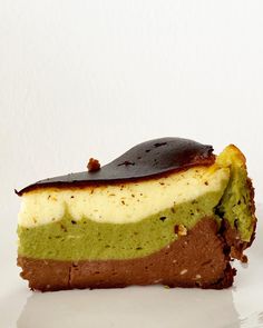 there is a piece of cake with chocolate and green frosting on the top, sitting on a white plate