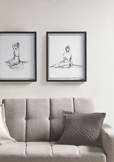 two framed pictures hang on the wall above a couch in a living room with pillows