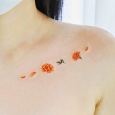 an orange flower tattoo on the back of a woman's shoulder