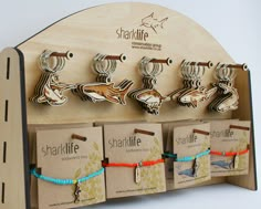 a wooden display with six different bracelets on it's hooks and tags attached to them