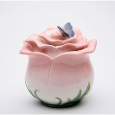 a pink flower vase with a butterfly on it's top sitting in front of a white background