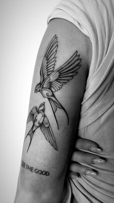 a black and white photo of a woman's arm with two birds on it