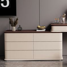 a white dresser with two vases on top of it next to a black and white clock