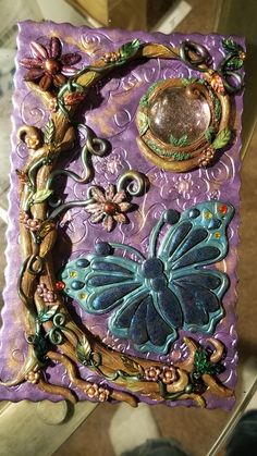 an intricately decorated purple and blue tile with butterflies on it's sides, surrounded by other decorative items