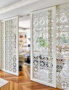 a living room with white walls and wooden floors in front of an open door to another room