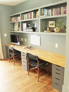 an office with two desks and several bookshelves on the wall above them