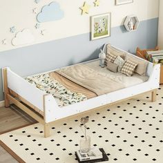 a white bed sitting on top of a wooden floor next to a wall filled with pictures