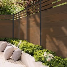 an outdoor seating area with pillows and flowers on the ground next to a wooden fence