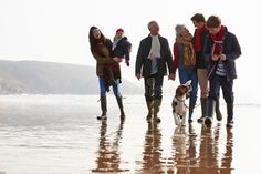 group of people walking on the beach with their dog