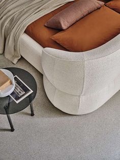 a bed sitting on top of a white floor next to a table with a book