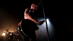 a man standing on top of a stage holding a guitar