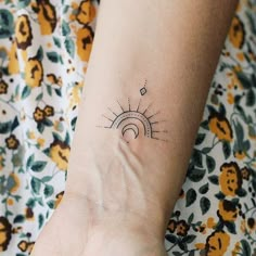 a woman's arm with a small sun tattoo on the left side of her wrist