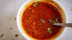 a white bowl filled with red sauce and garnished with parsley