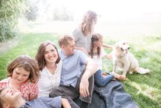 a family sitting on the grass with their dog