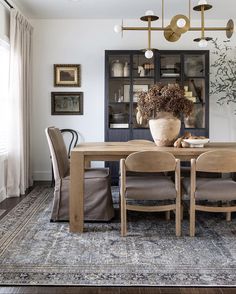 a dining room table with chairs and a vase filled with flowers on top of it