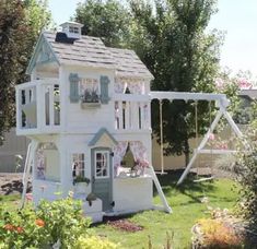 a doll house with a swing set in the yard