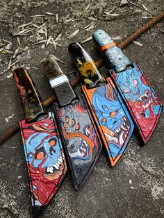 four different colored knives laying next to each other on the ground with graffiti painted on them