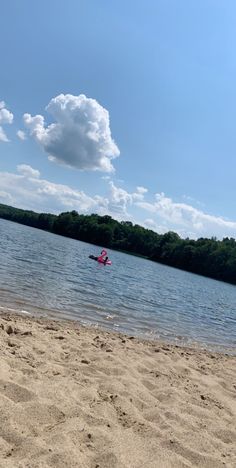 a boat floating on top of a lake next to a sandy beach