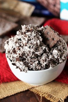 a bowl filled with chocolate ice cream on top of a red cloth next to a wooden table